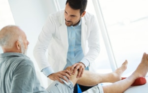 Senior man having his knee examined by a doctor.