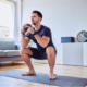 man doing squats with kettlebell weights at home.